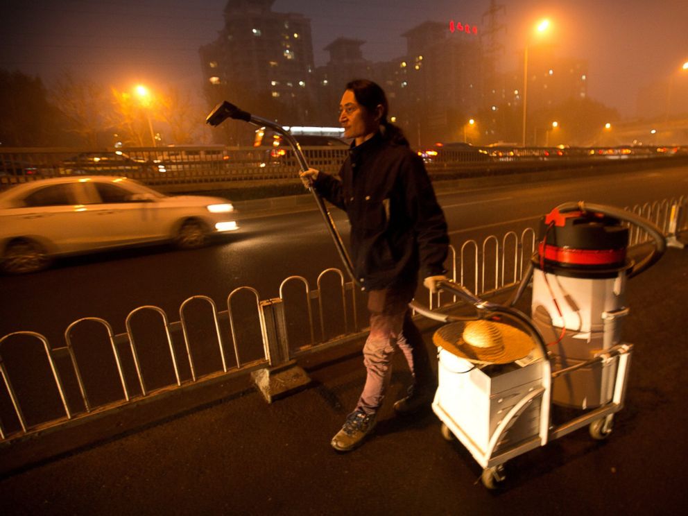PHOTO: Chinese artist Wang Renzheng walks along a highway as he demonstrates the use of his industrial shop-vac in Beijing, Dec. 1, 2015.